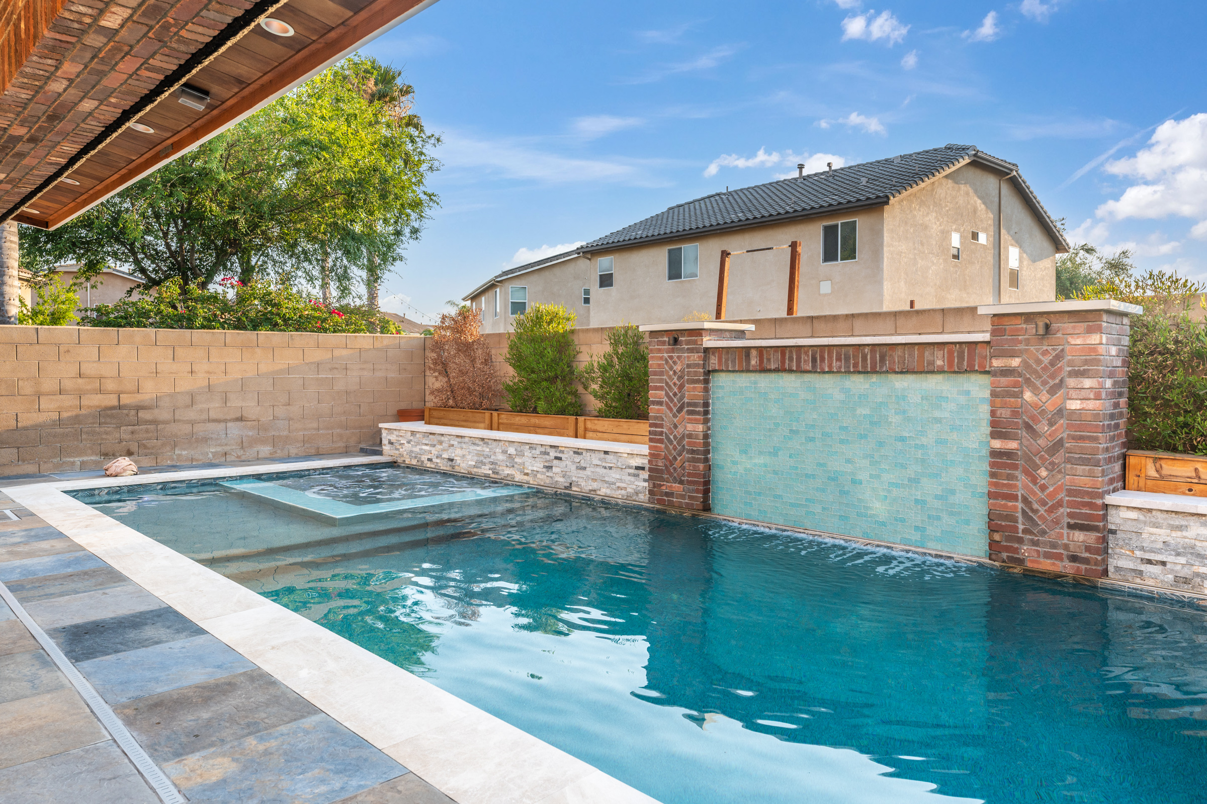 Pool and spa with raised glass tile wall