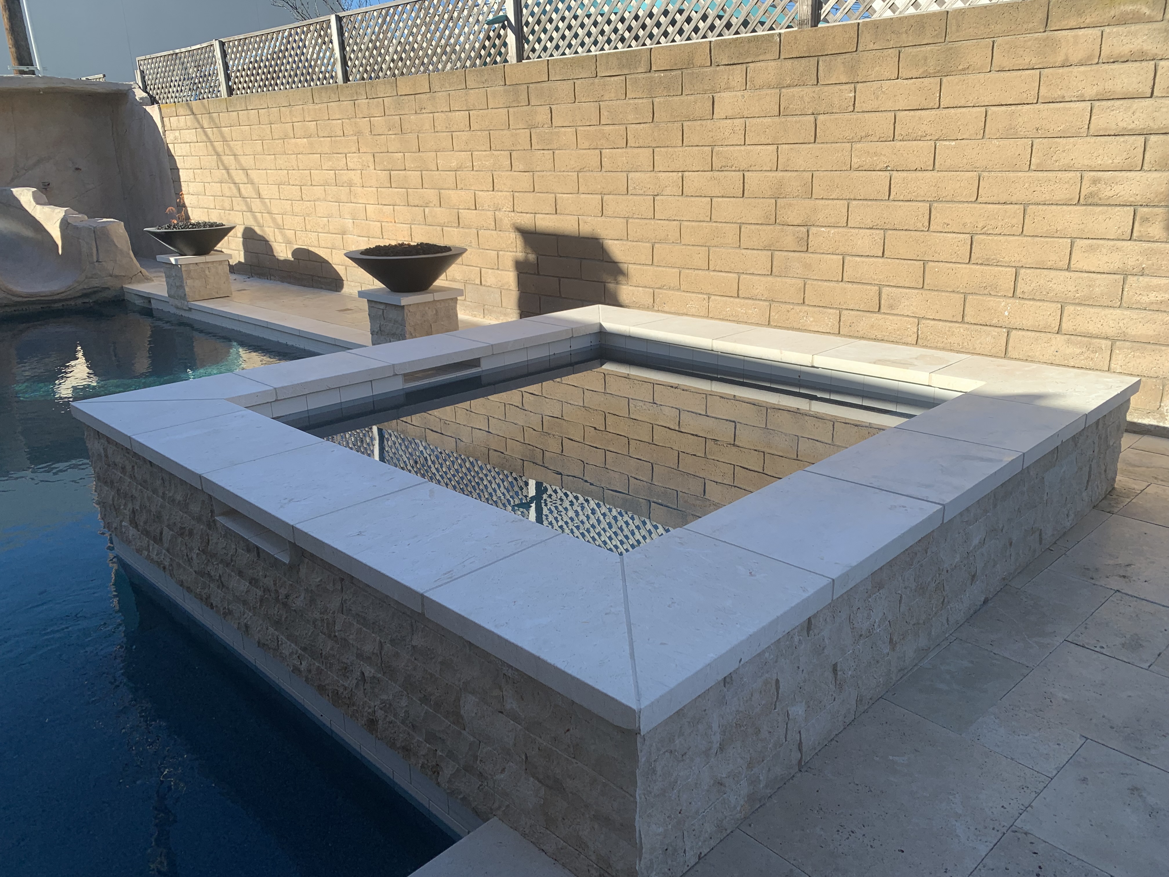 Raised spa with aqua glass tile waterfall wall and brick columns